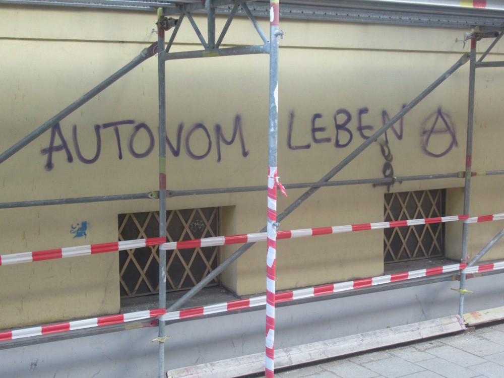 Der Schriftzug "Autonom Leben" an einer Hauswand hinter einem Baugerüst