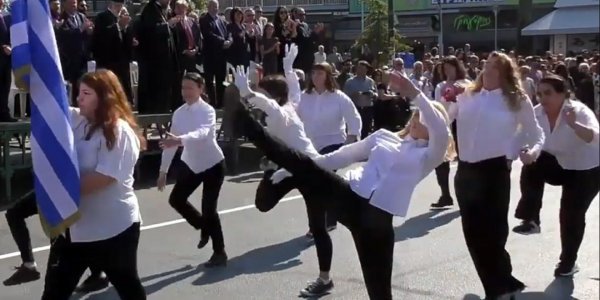 Frauen in schwarzen Hosen und weißen Hemden demonstrieren mit einem "silly walk" gegen Nationalismus und Militarismus in Griechenland