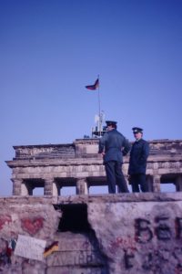 Zwei Volkspolizisten stehen im Frühjahr 1990 auf der angebrochenen Mauer am Brandenburgertor.
